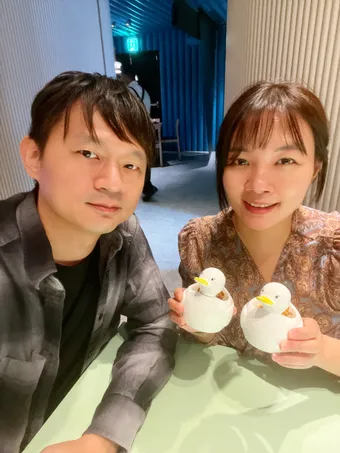 兩人拿著成對的鴨子造型甜點合照