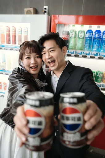 兩人在販賣機前舉百事可樂乾杯